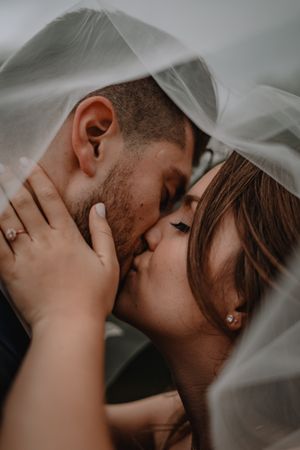 bride and groom kissing under a veil
