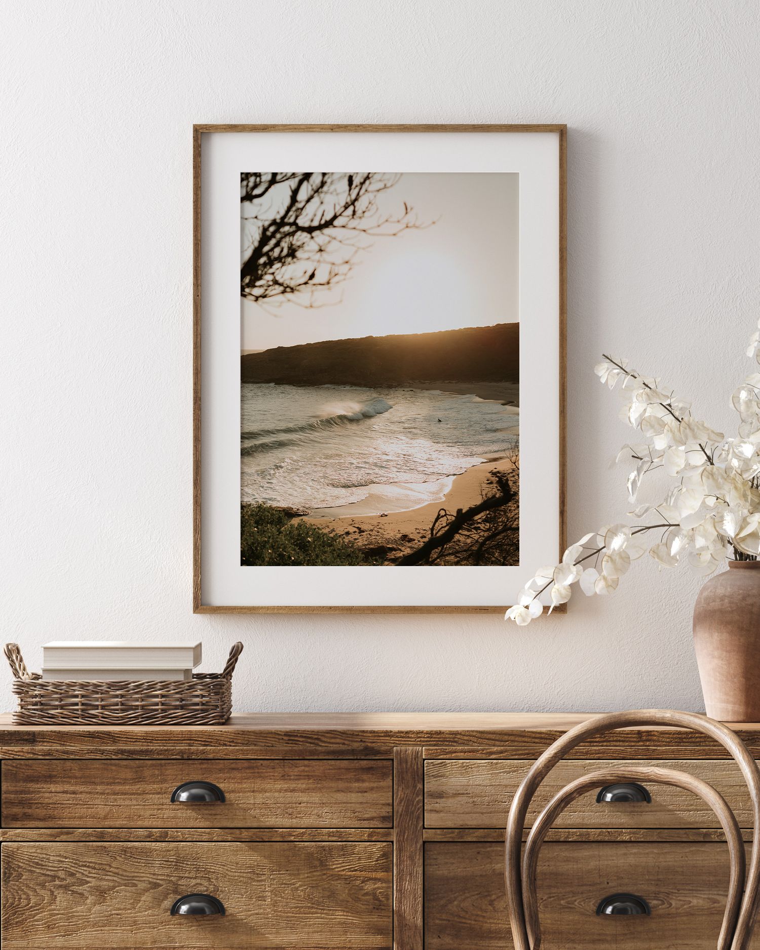 Moody black and white coastal landscape photograph in wooden frame on rustic dresser.