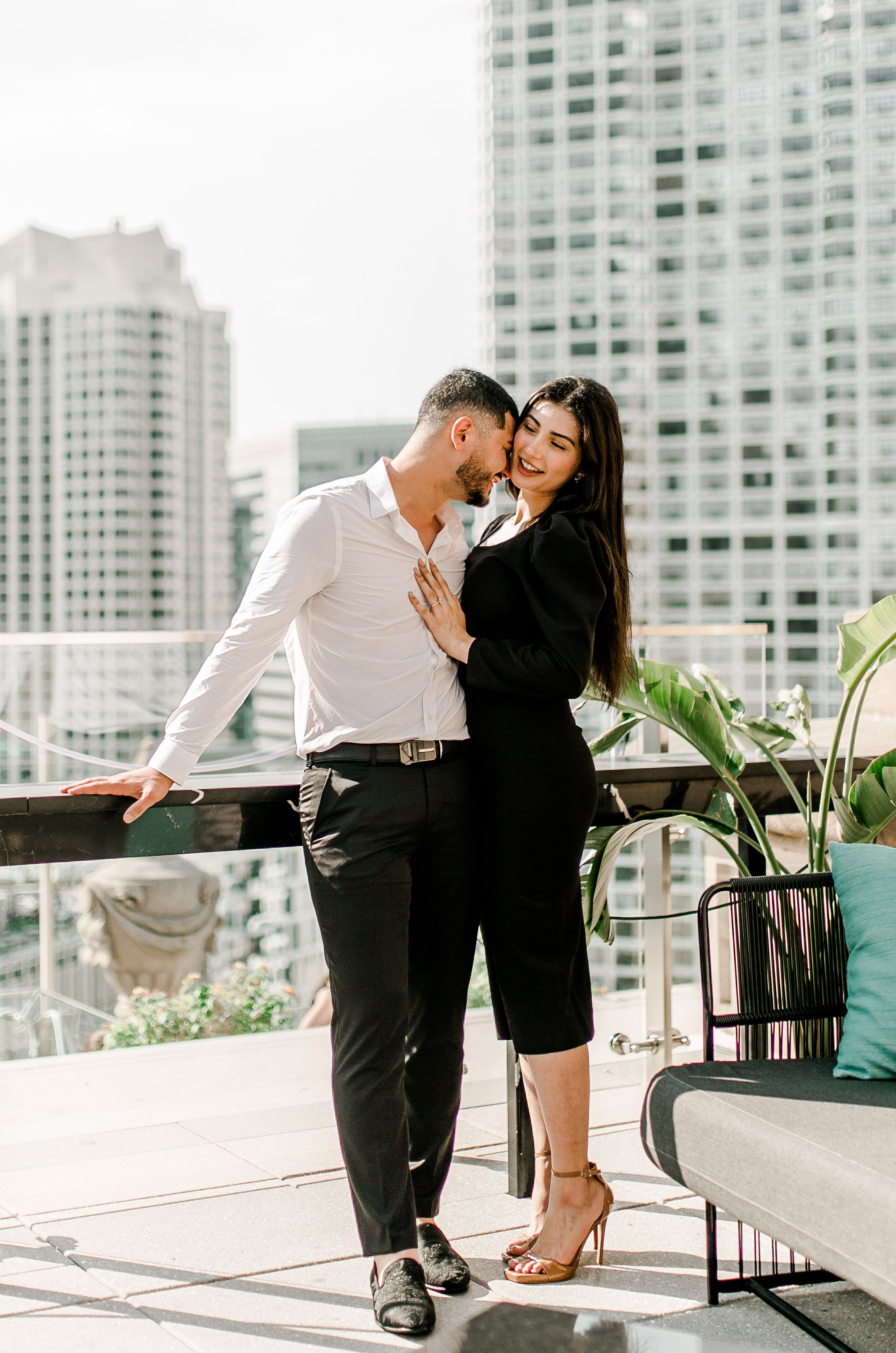 Romantic couple embracing on urban rooftop with city skyline backdrop.