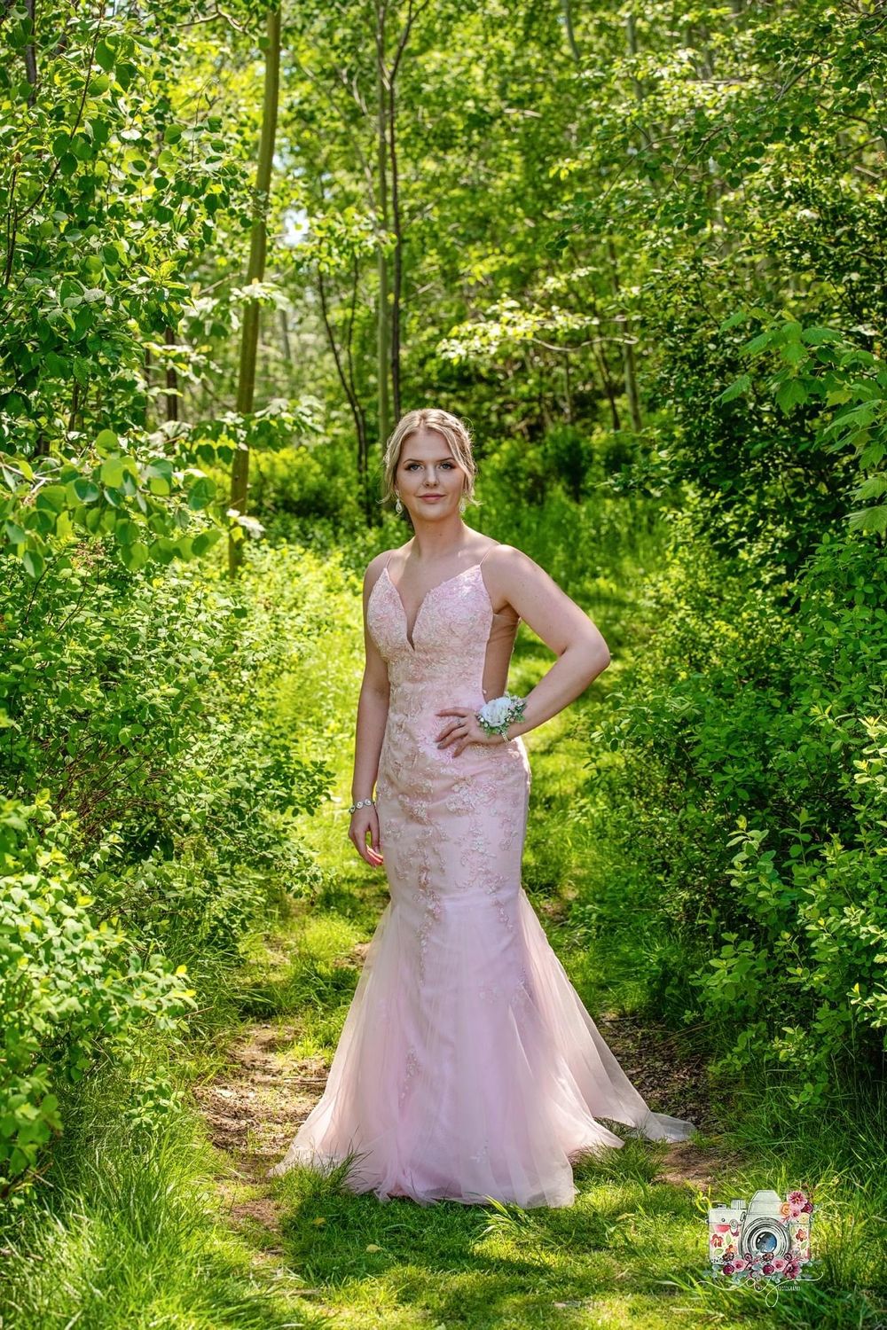 Fitted blush mermaid wedding dress showcased in a enchanted forest pathway.