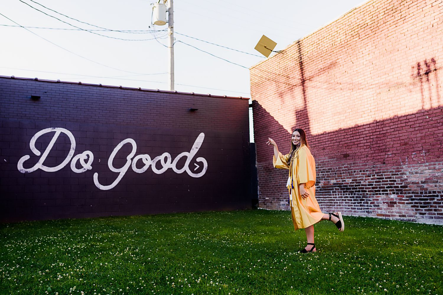 high school senior girl standing in front of brick building with sign