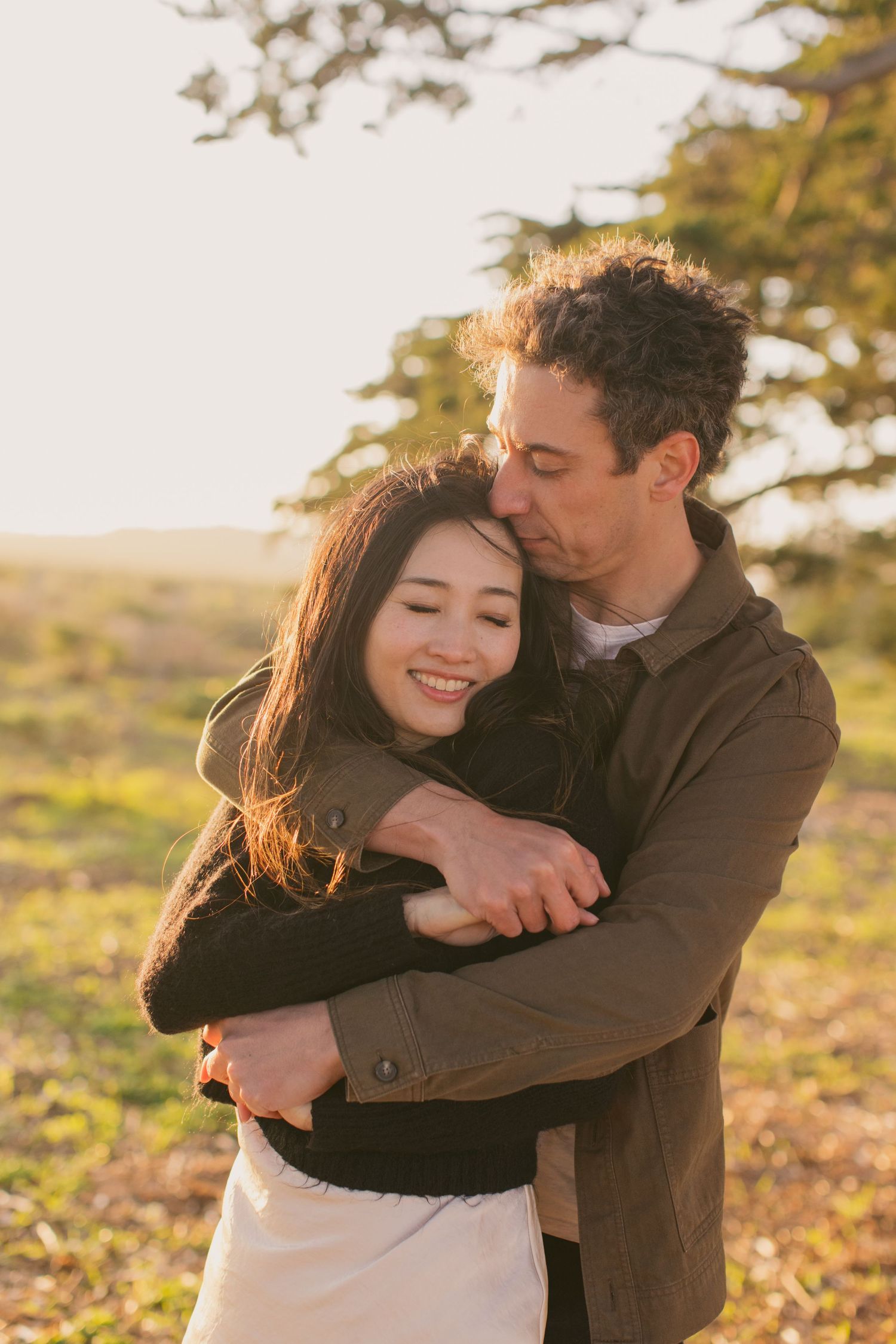 A tender embrace shared between a couple in warm sunset lighting.