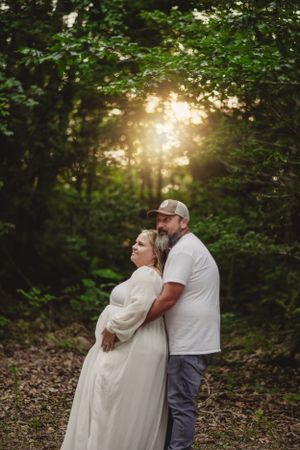 A tender embrace in a sunlit forest with golden rays filtering through trees.