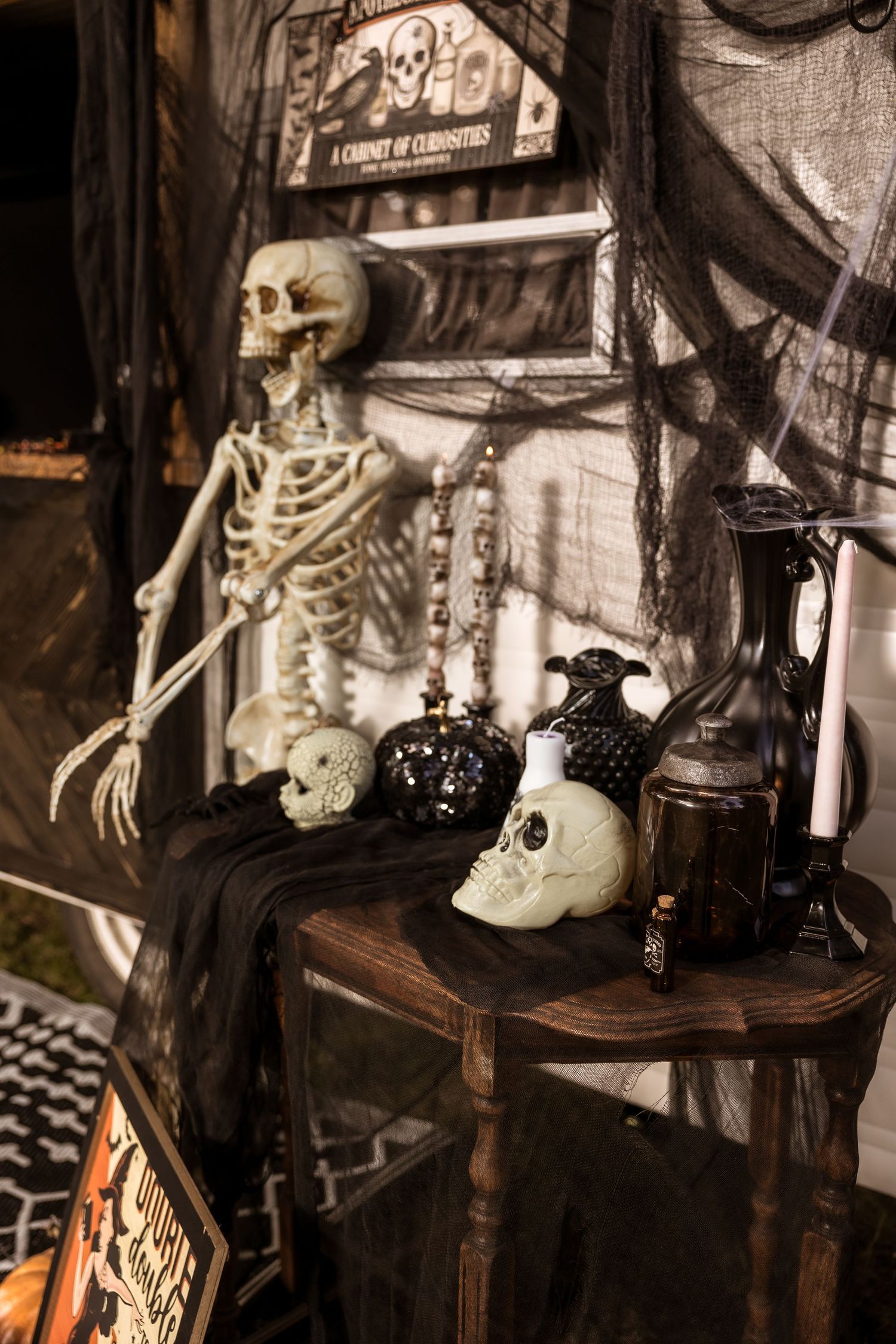 Vintage Halloween display with skeleton props, skulls, and antique bottles on dark fabric.