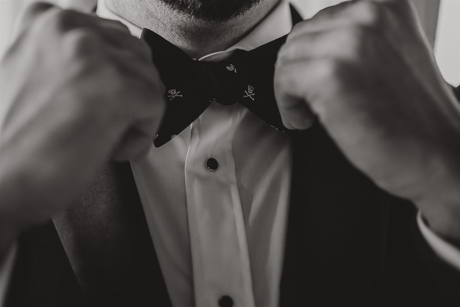 Close-up black and white photo of hands adjusting a bow tie.