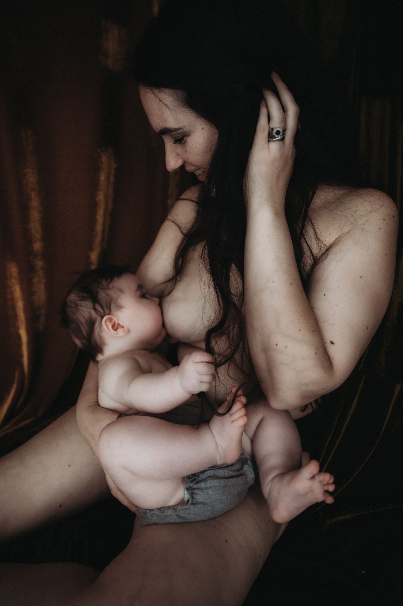 Mother breastfeeding her baby in soft natural light, focused on connection and closeness.