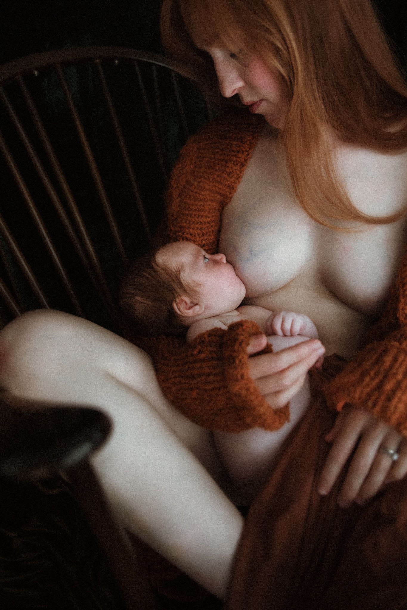 red headed mother breastfeeding her baby wearing an orange cardigan