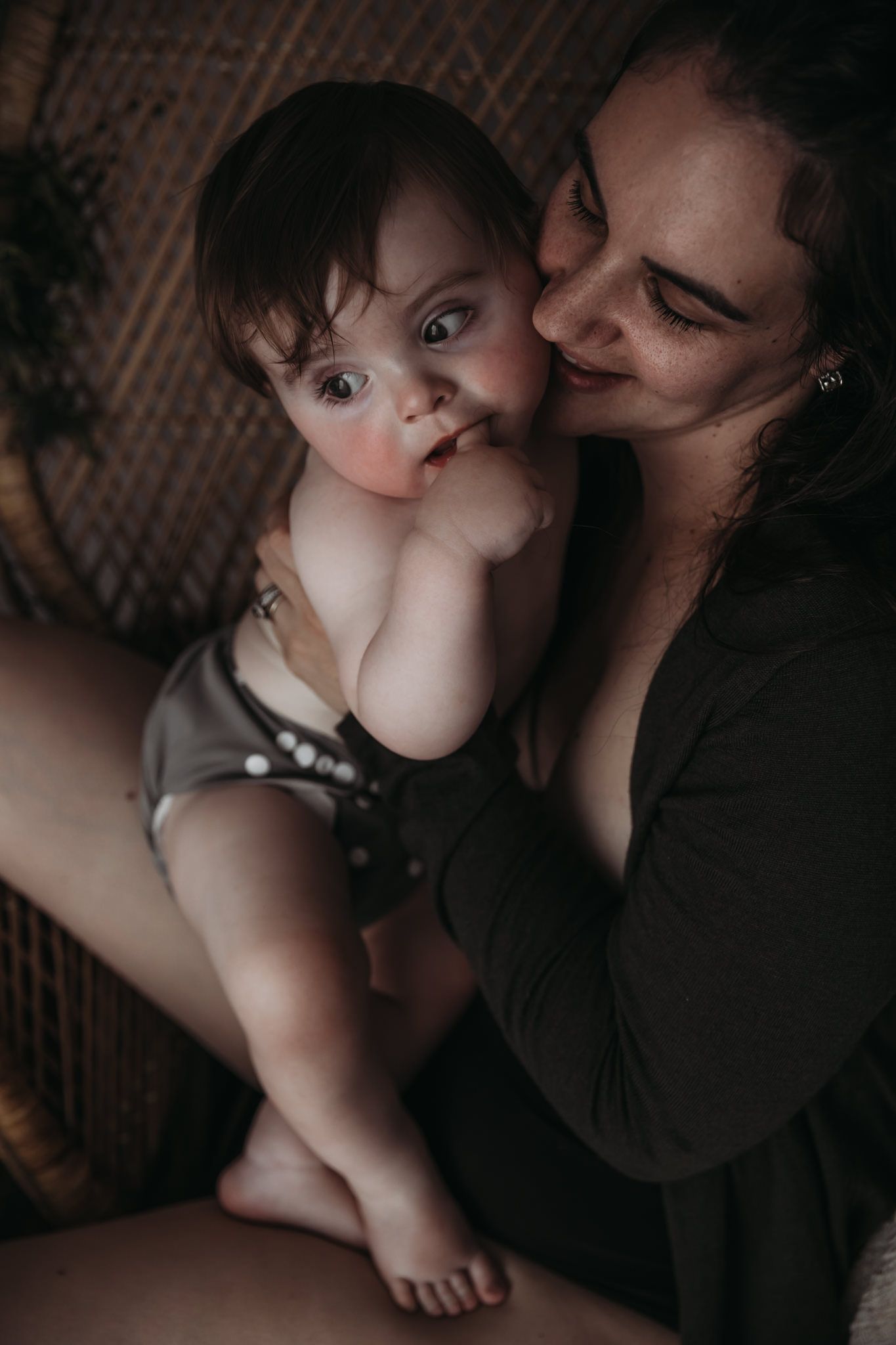 Mother holding her baby close against her chest, sharing a quiet, intimate moment indoors.
