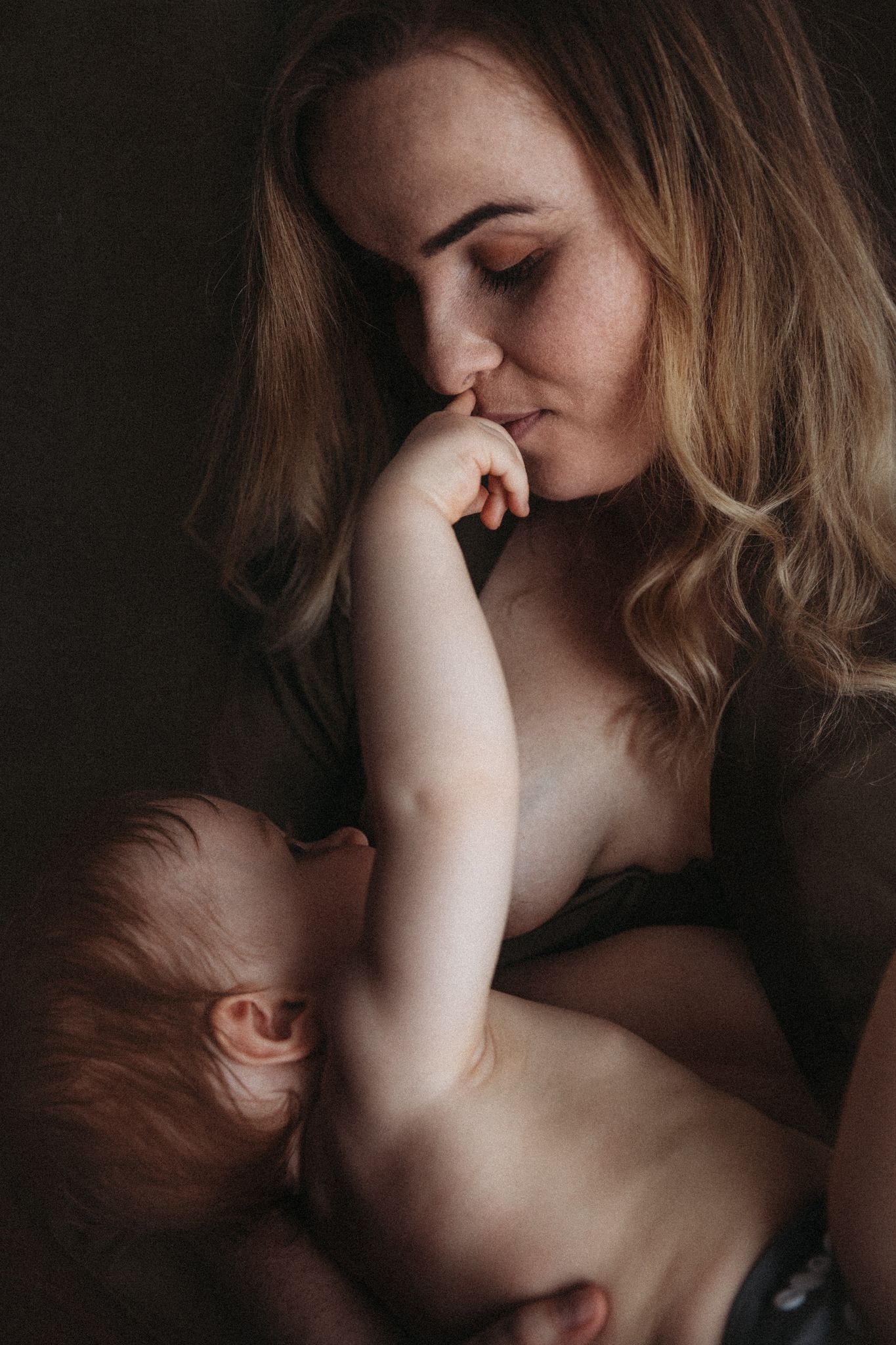 Mother and baby resting together in a quiet, tender moment, lit by soft window light.