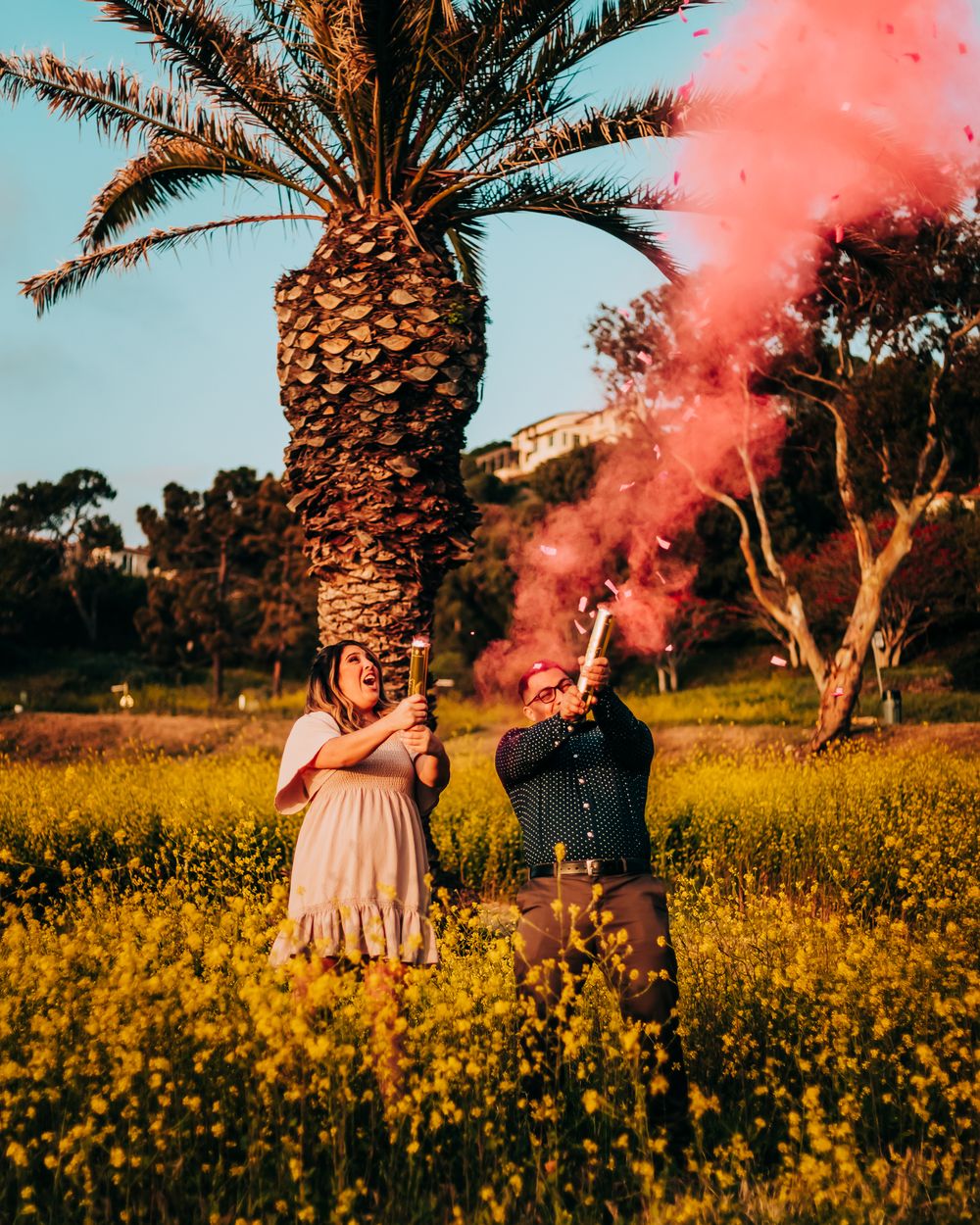 gender reveal smoke and confetti canon couple photography in field of flowers in Southern California