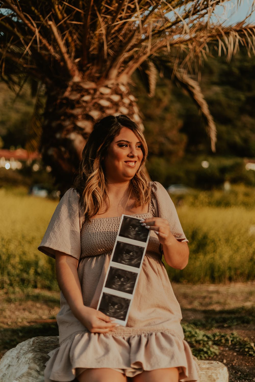 Pregnancy announcement photography of girl holding ultrasound in a field of flowers in Palos Verdes, California