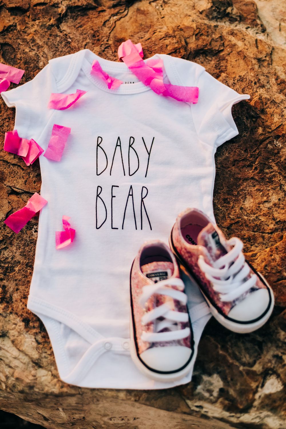 pregnancy announcement of baby's gender with a baby bear onesie and pink baby converse shoes