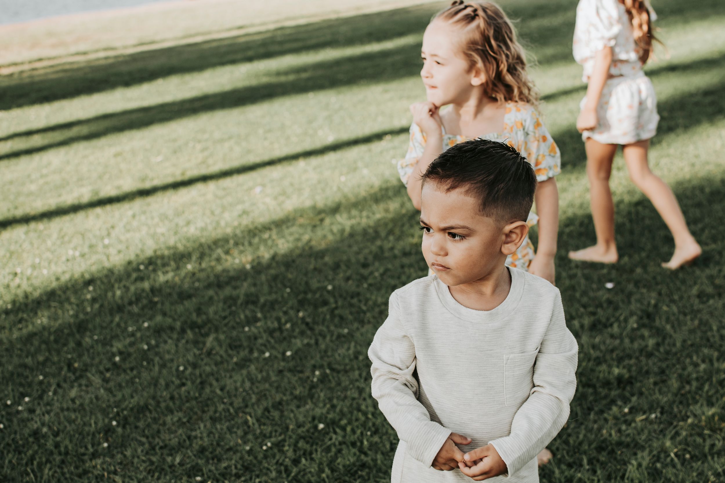 Children playing on a grassy lawn during golden hour.