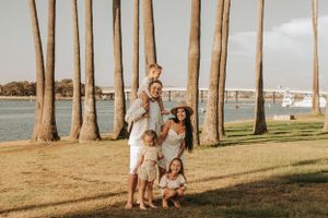 Children playing together among tall palm trees at sunset in a grassy coastal park.