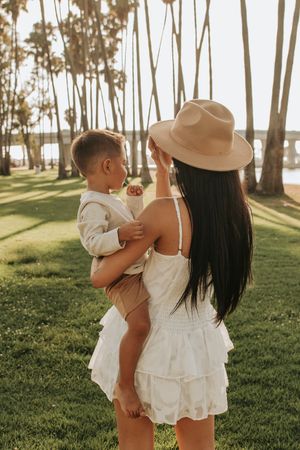 Family in white outfits sharing tender moments among palm trees at golden hour.