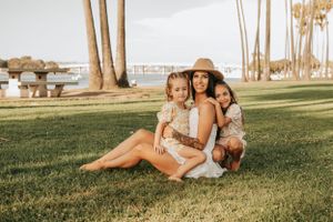 Relaxed outdoor photoshoot on grass with palm trees and natural lighting.