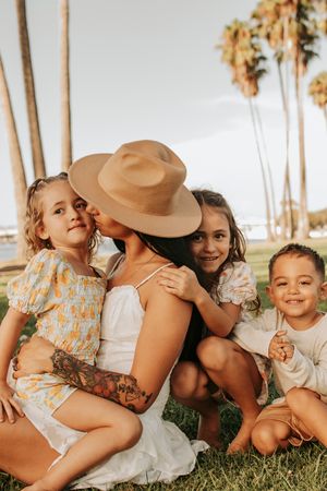 Playful outdoor family moments captured on green grass with tropical palm trees in background.