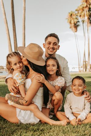 Joyful family bonding time during outdoor photo session with palm trees.