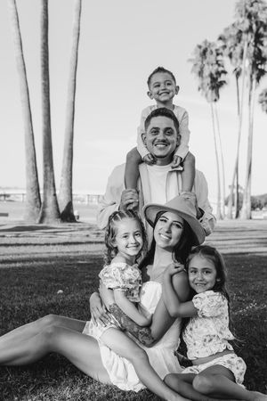 Black and white family portrait with palm trees showing playful interactions.
