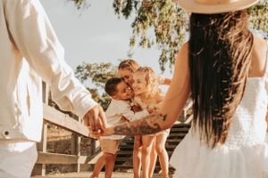 Playful family interaction captured in warm sunlight on outdoor staircase.