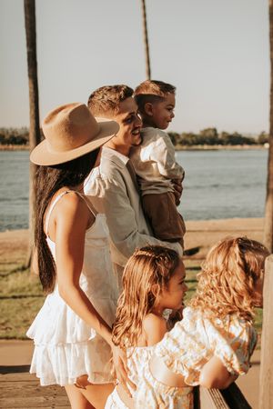 Family shares tender moment together on boardwalk with palm trees and water view.
