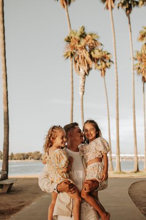 Sweet family interaction captured against palm tree backdrop at golden hour.