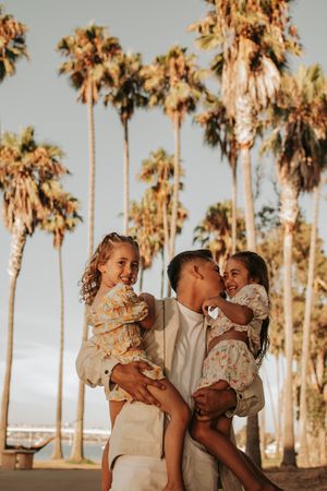 Candid family moment with palm trees silhouetted against warm sunset sky.