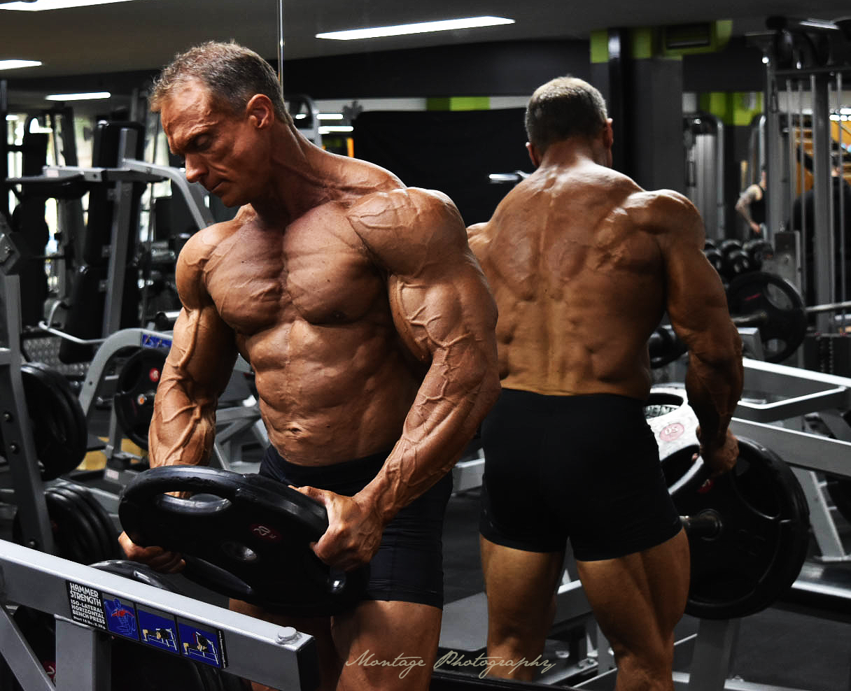 Bodybuilder with muscular physique training in a modern gym with fitness equipment.