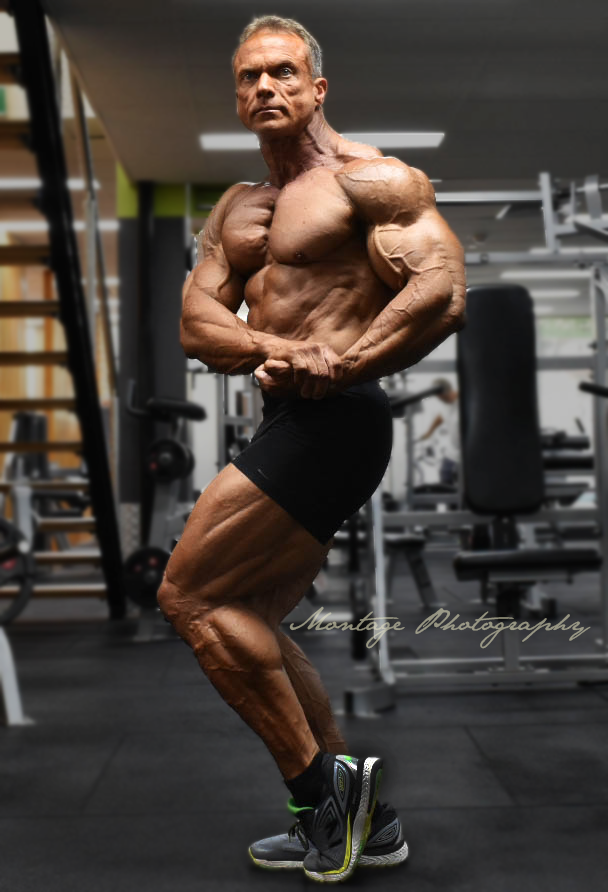 Professional bodybuilder striking classic pose in modern fitness facility.