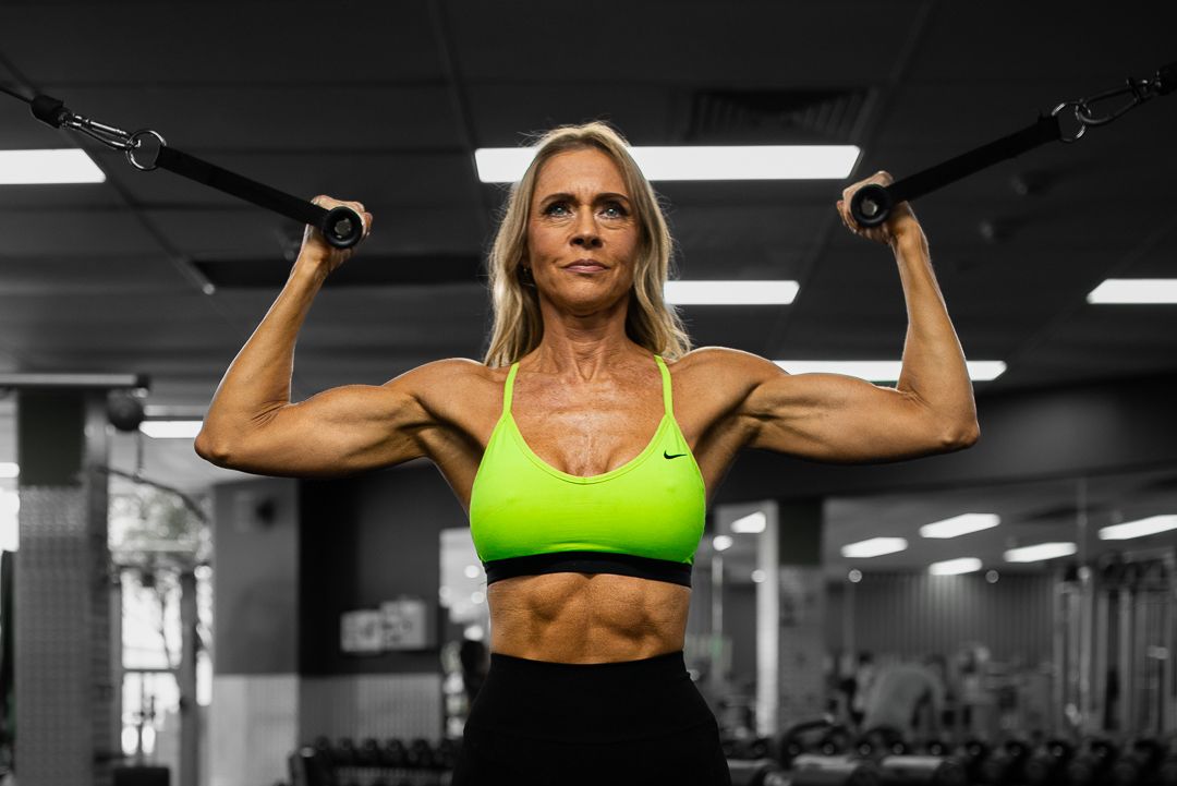 Strong athlete performing lat pulldown exercise in bright sports wear at the gym.