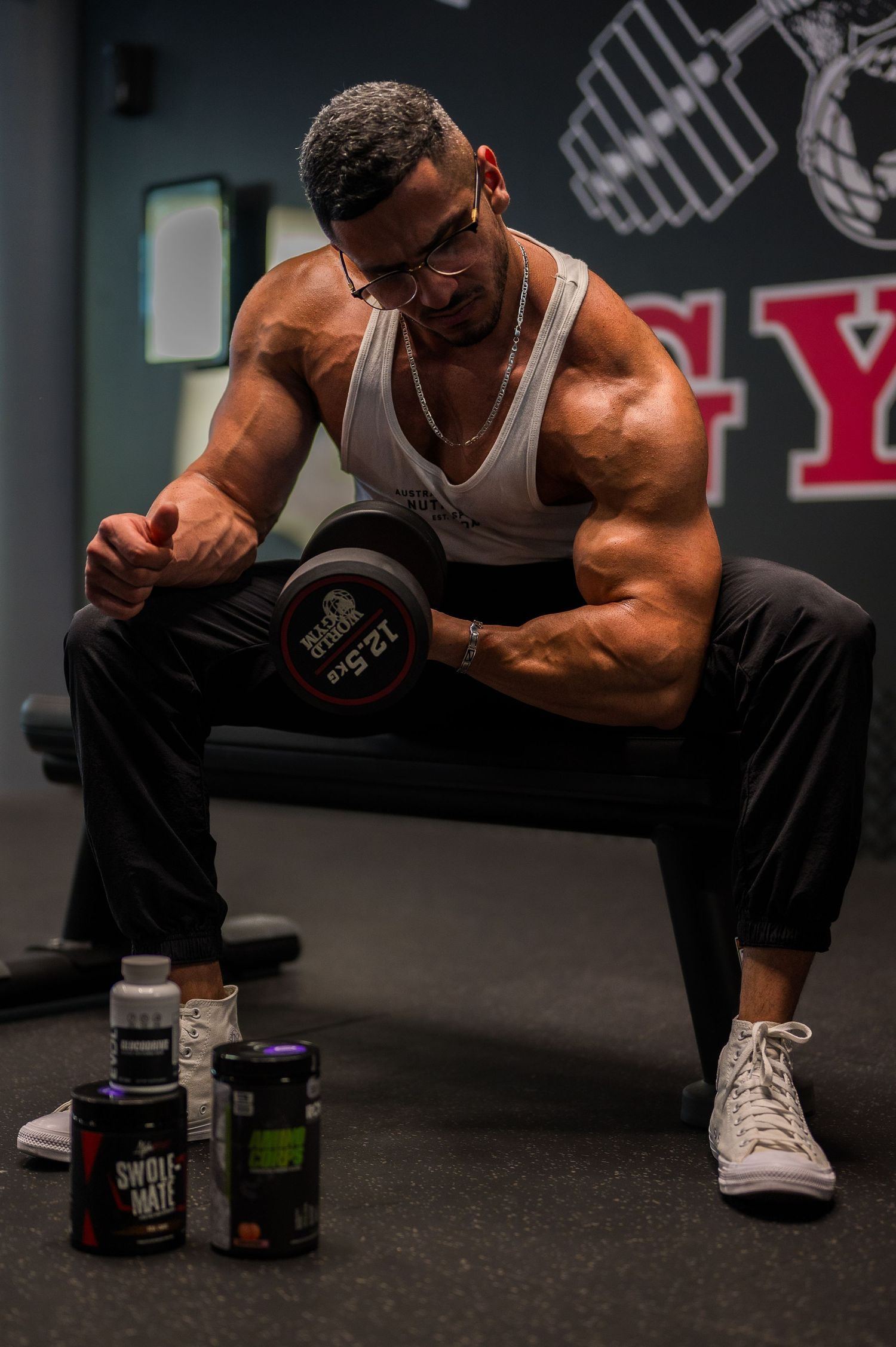 Muscular athlete during workout session with supplements visible in foreground.
