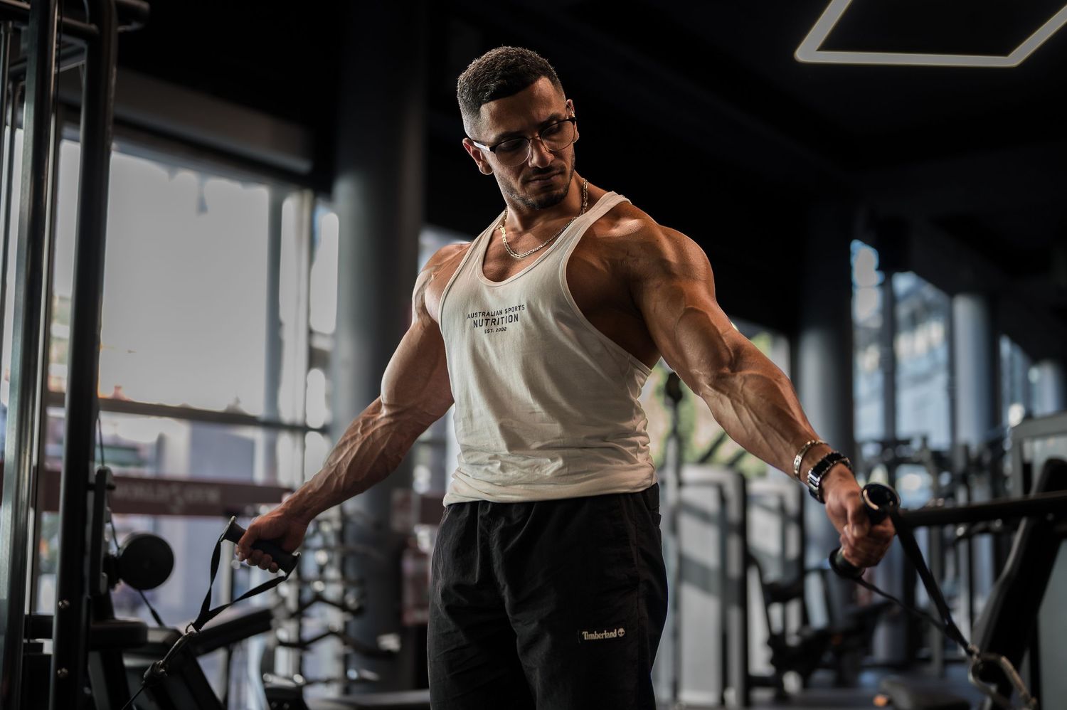 Athletic figure performing cable machine exercises in a well-equipped gym.