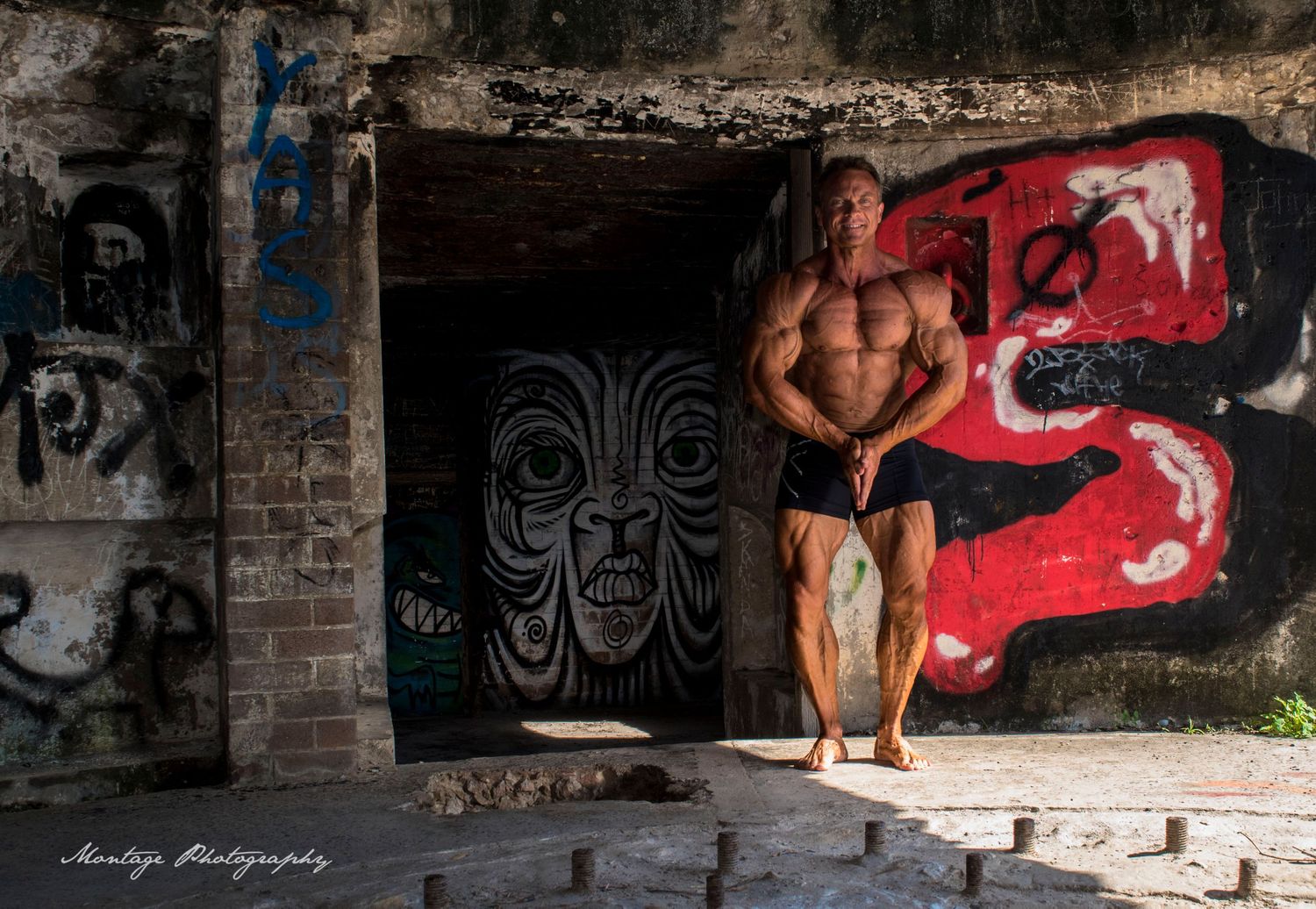 Athletic physique displayed against urban graffiti wall in dramatic lighting.