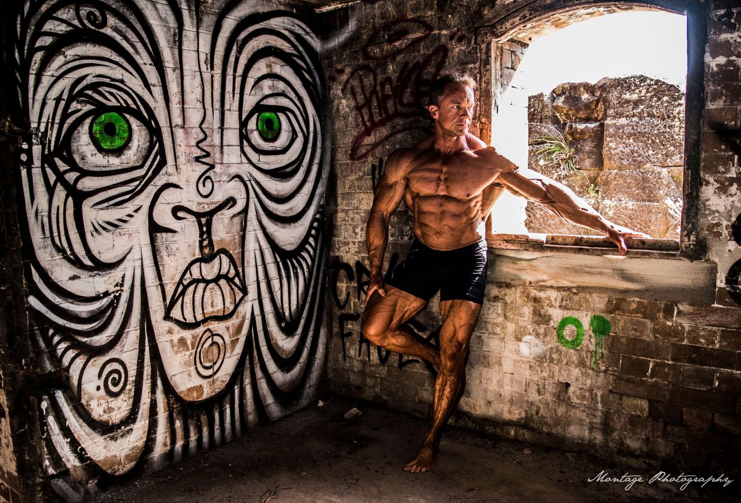 Athletic figure in an urban setting with dramatic street art featuring a large tribal face design on the wall.