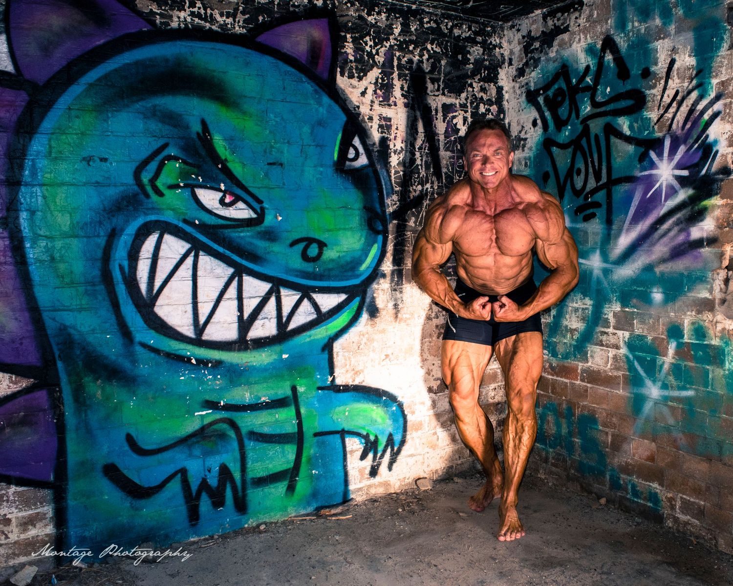Athletic figure standing next to large teal cartoon monster graffiti on brick wall.