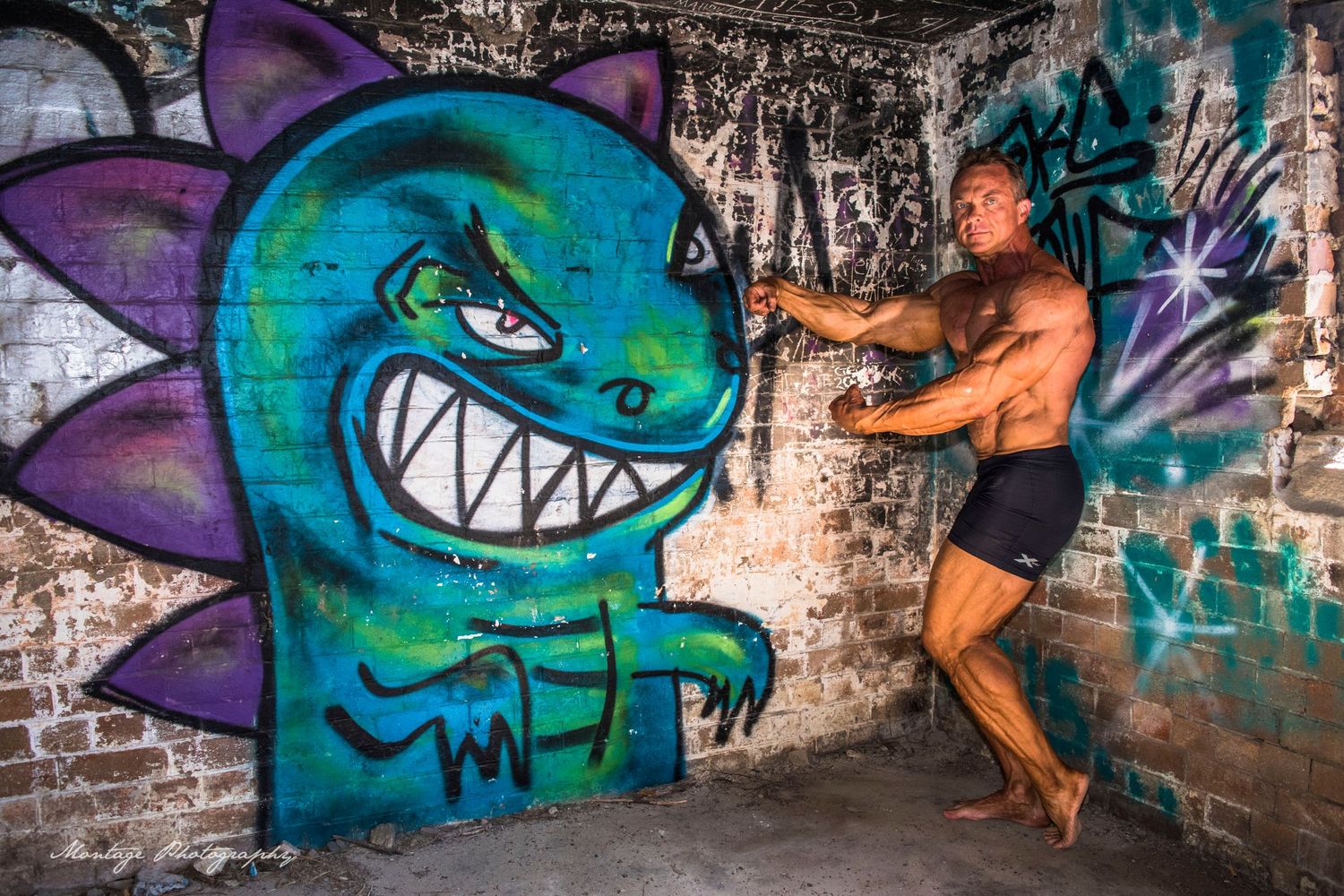 Bodybuilder interacting playfully with large cartoon dinosaur street art on brick wall.