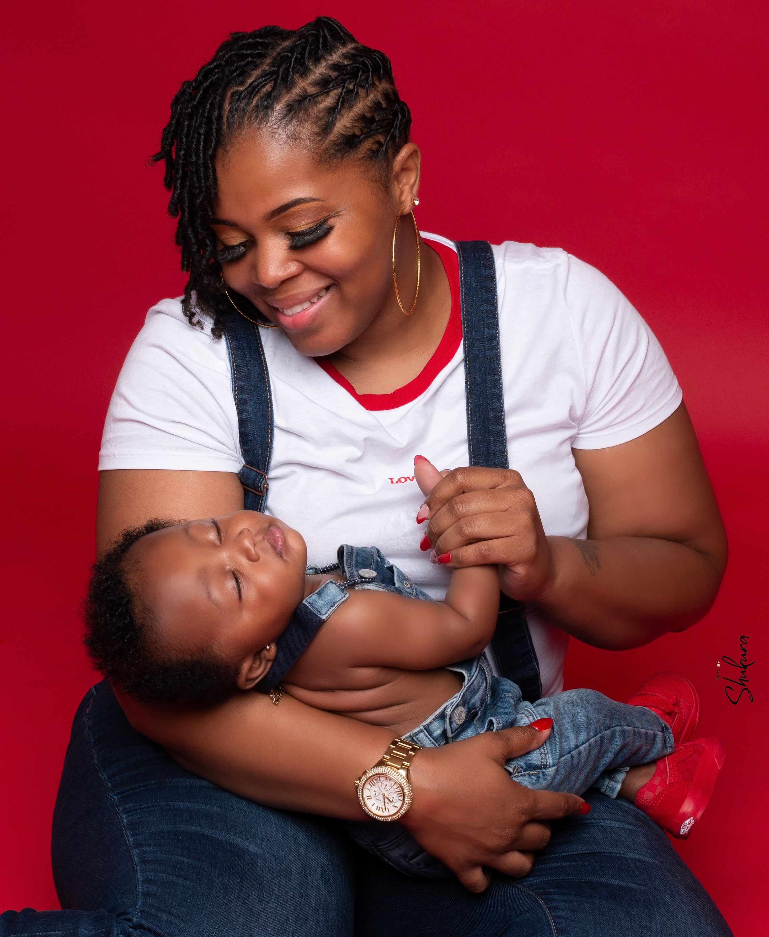Parent and baby sharing a joyful moment against red background.