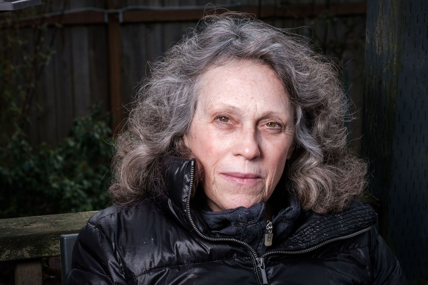 Person in a black winter coat with curly gray hair photographed outdoors in a series of close-up shots.