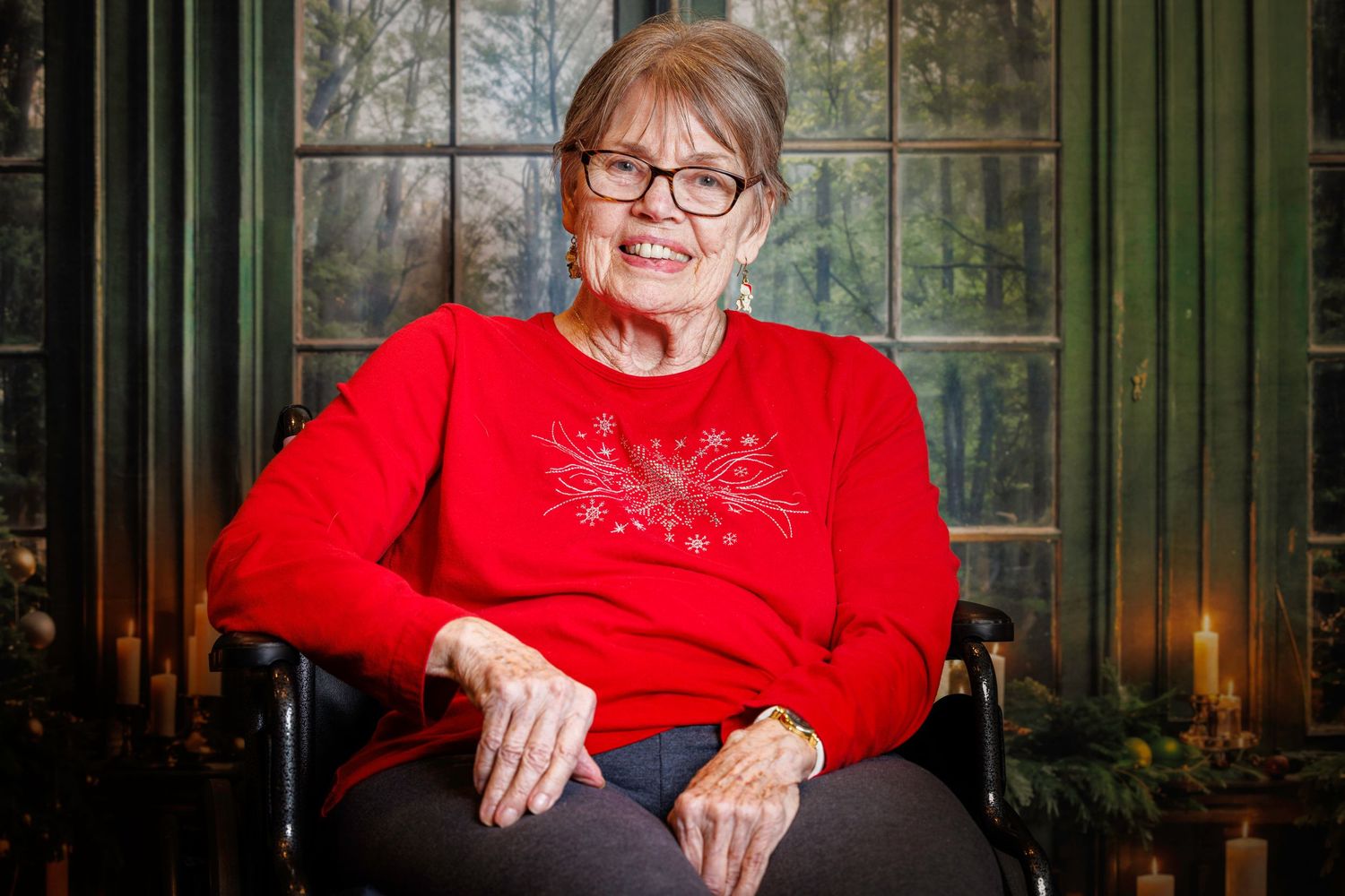 Person in bright red sweater sits by window in sunlit room with plants visible outside.