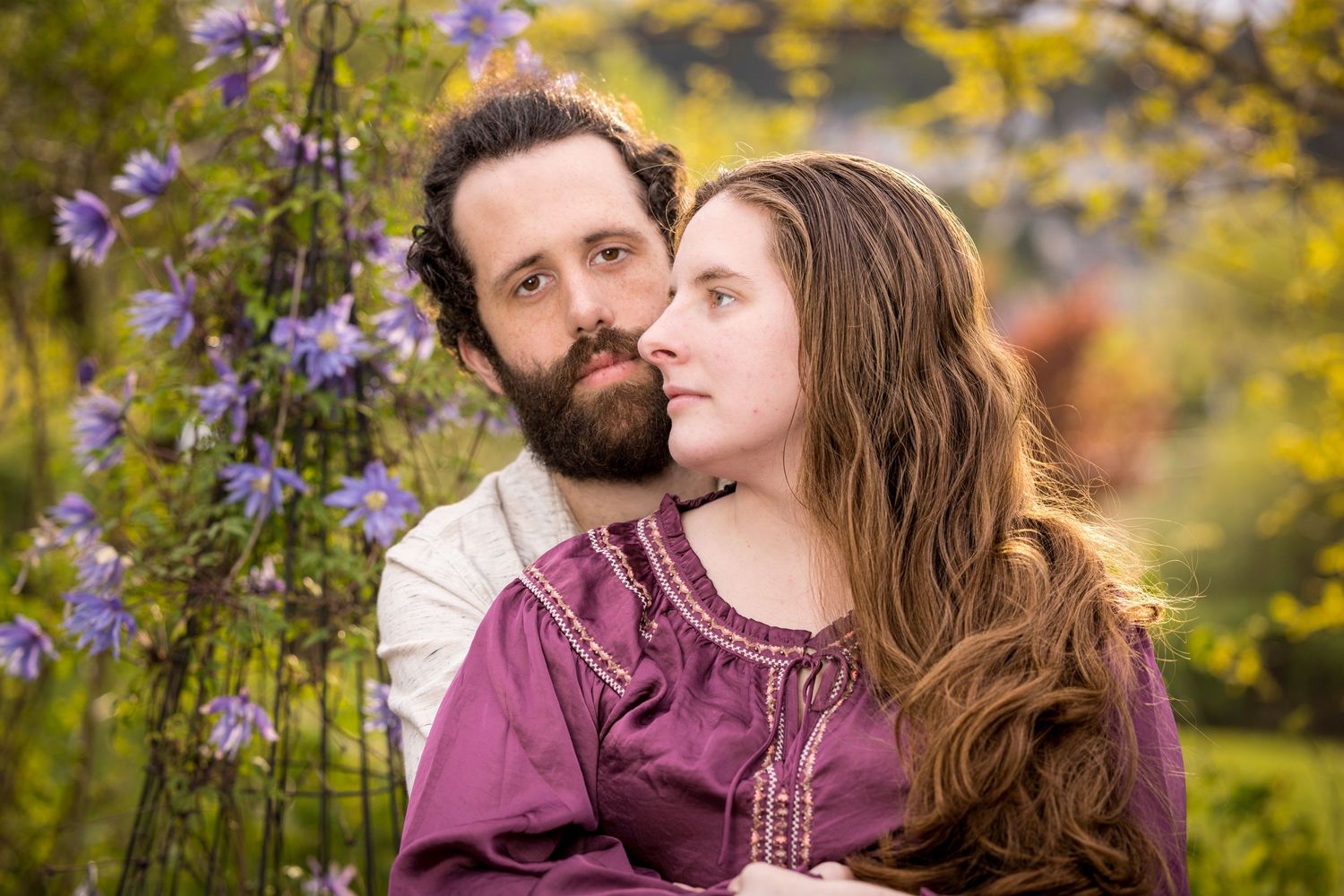 Romantic couple sharing an intimate moment among purple wildflowers and yellow foliage.