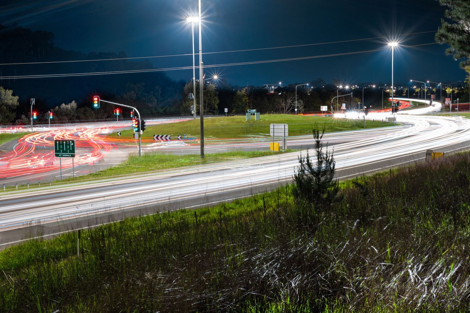Long exposure night shot of a highway with light trails and illuminated street lamps.
