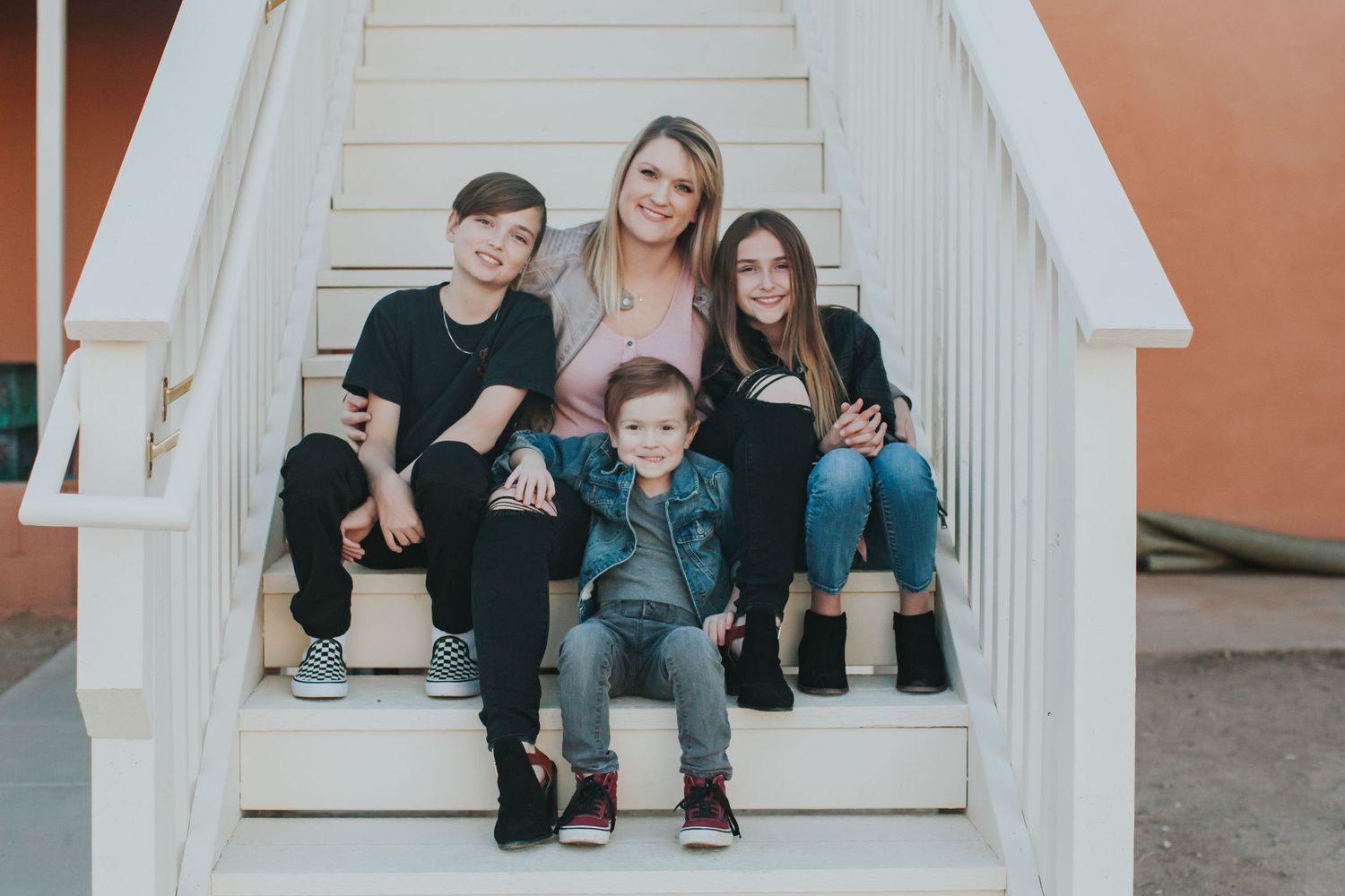 Family portrait on white wooden stairs of a small structure.