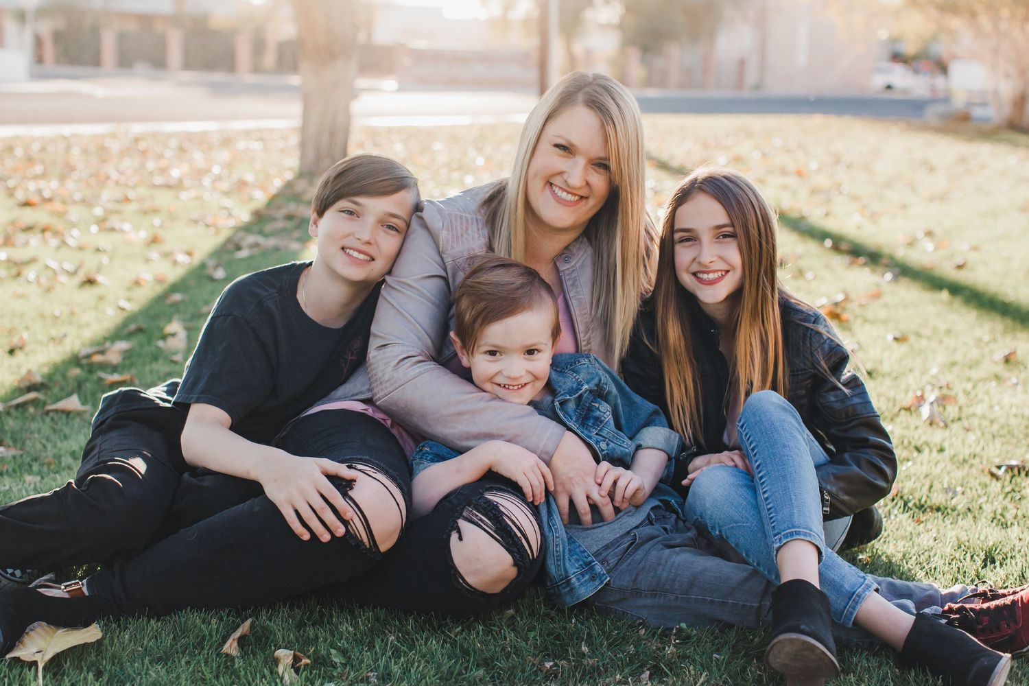 Family group relaxes together on grass during outdoor photo session.