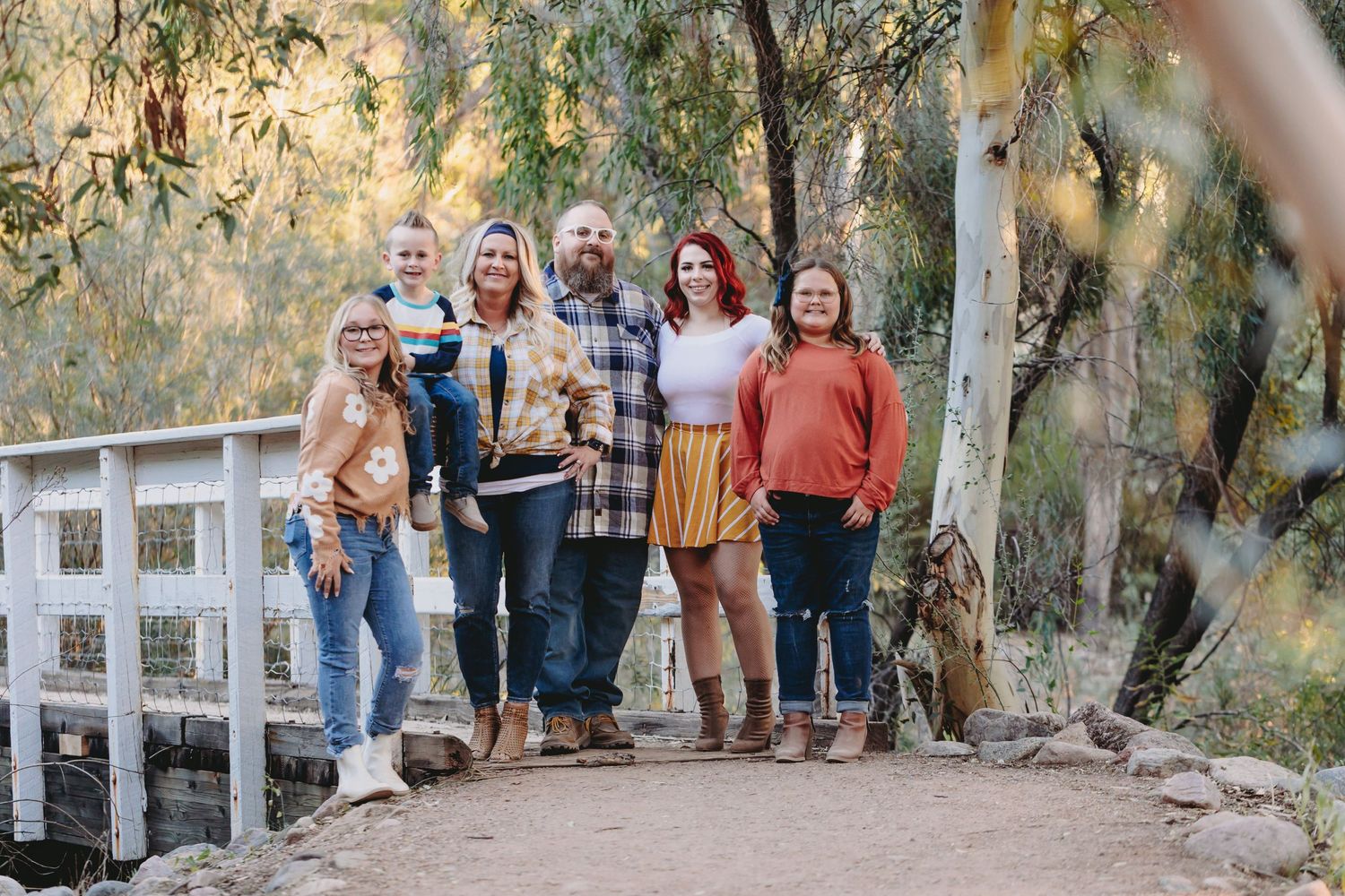 Friends gathered on a rustic wooden bridge path surrounded by trees.