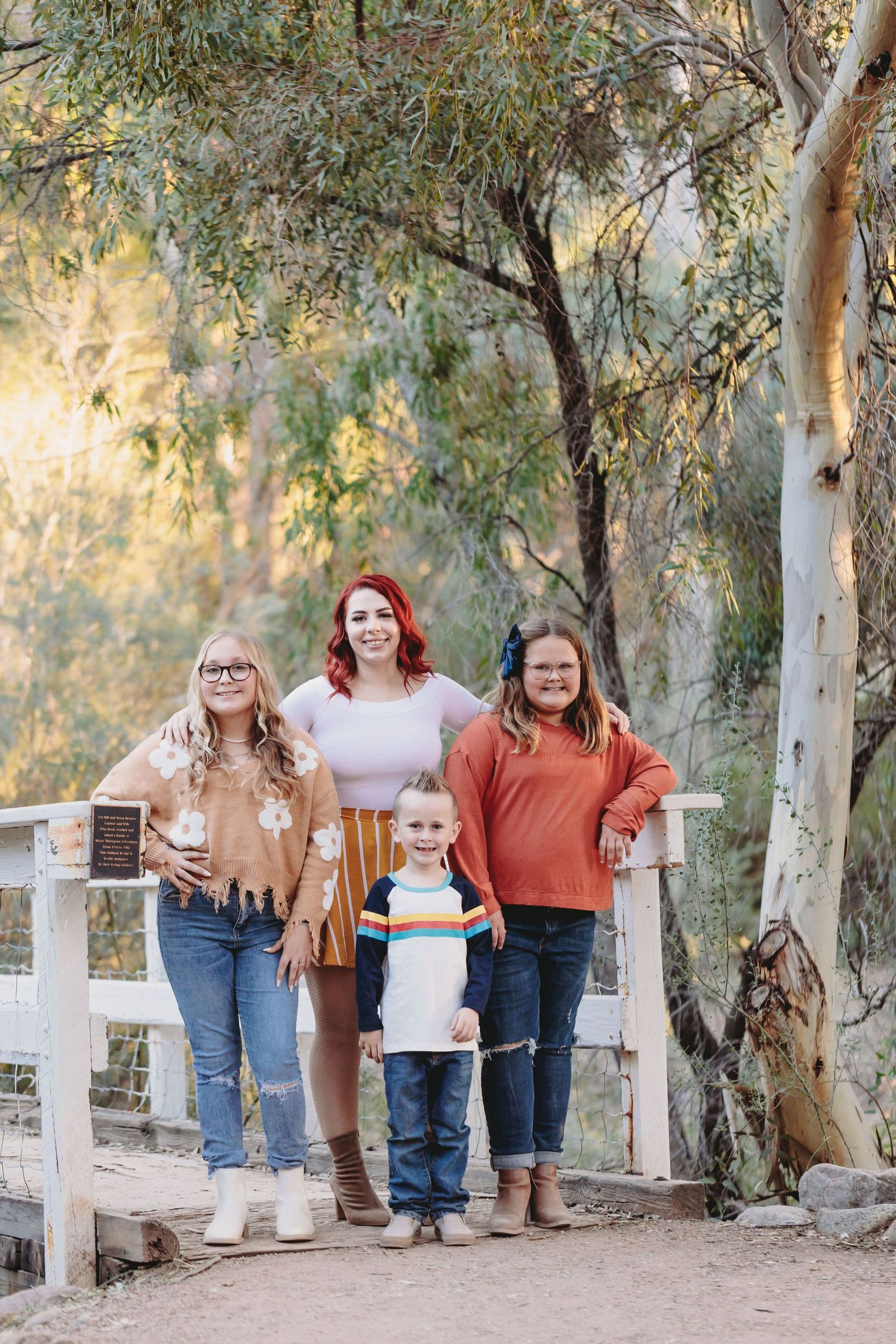 Group photo on a wooden walkway surrounded by eucalyptus trees at sunset.