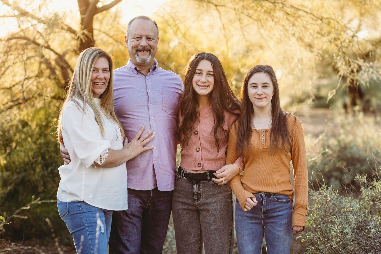 Group photo against a golden autumn backdrop with trees and warm sunset lighting.