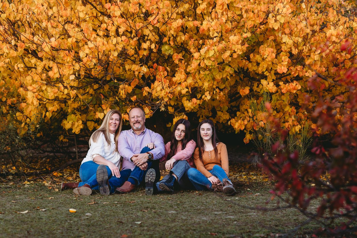 Family portrait session with autumn foliage creating vibrant orange backdrop.