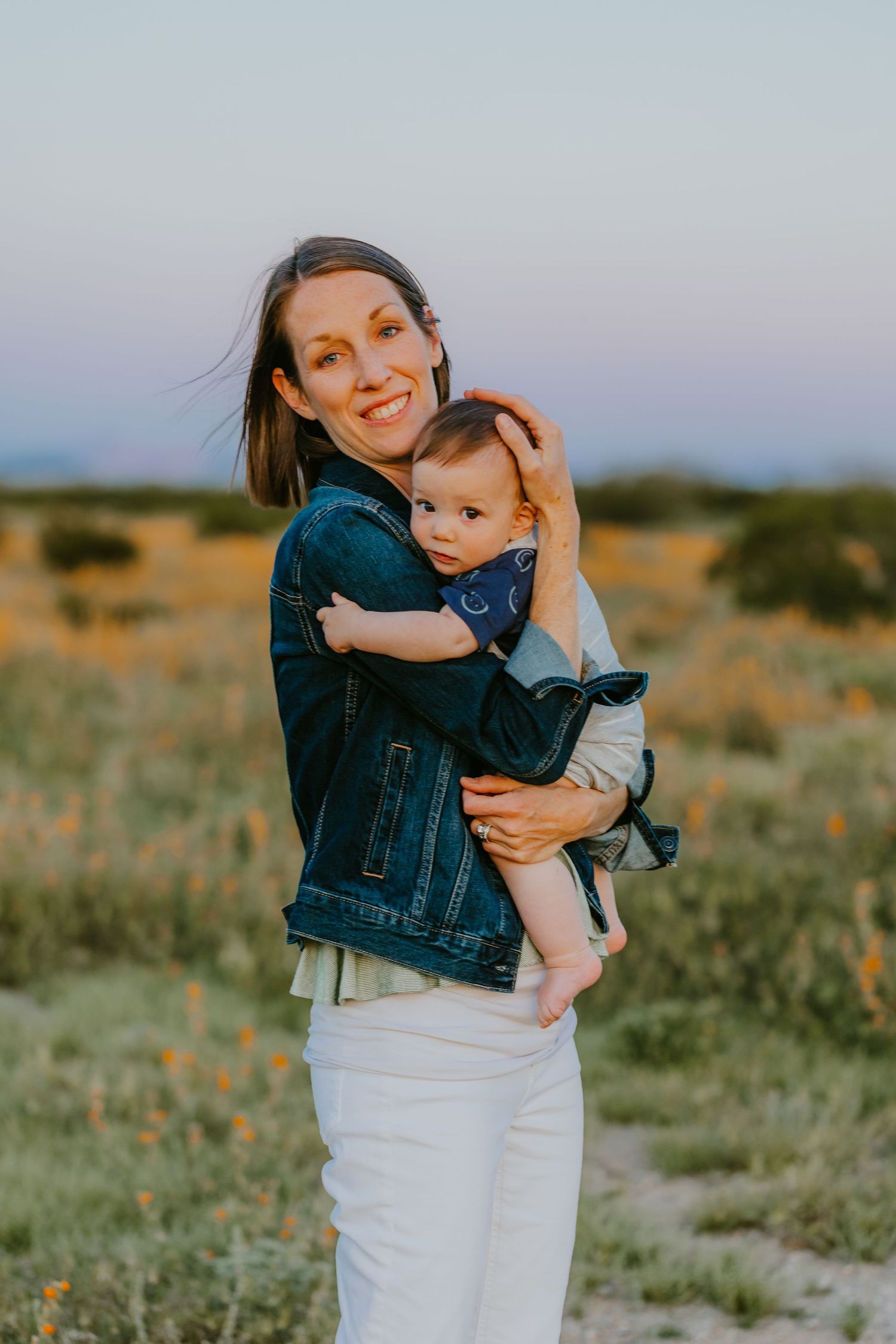 A tender moment captured between parent and baby against a desert backdrop at sunset.