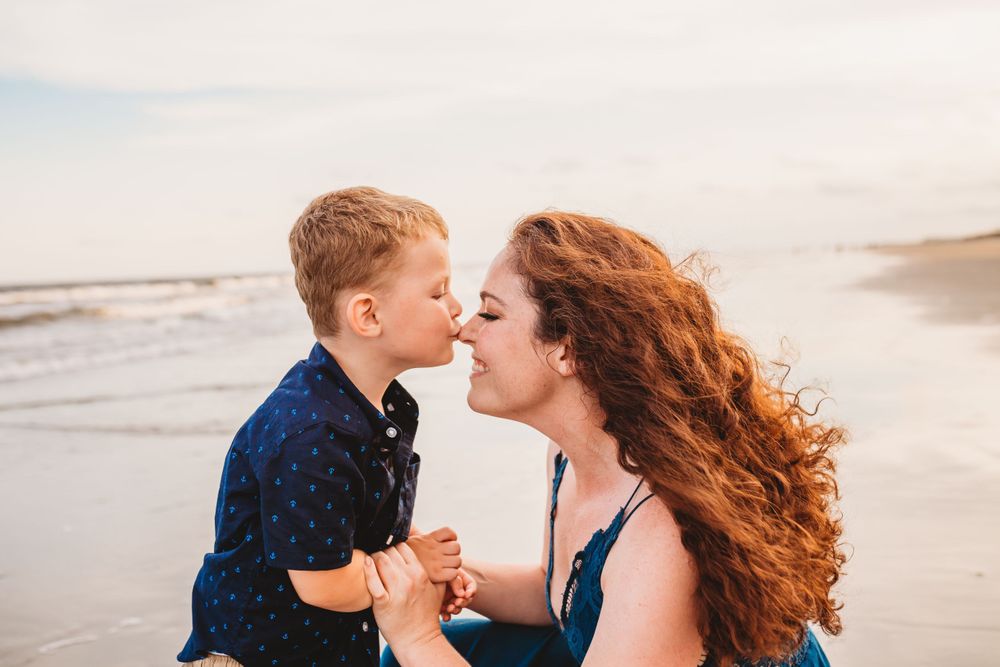 A sweet beachside moment shared between parent and child with ocean waves in background.