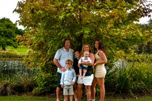 Family photo session in a lush green park setting during golden hour.